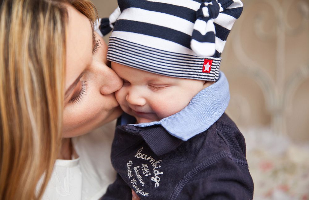 A mother kissing a young child on the cheek